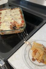 Homemade lasagna recipe with cottage cheese being served fresh from the pan with melted mozzarella cheese stretching onto the plate. A simple 4-generation family lasagna recipe without ricotta cheese.