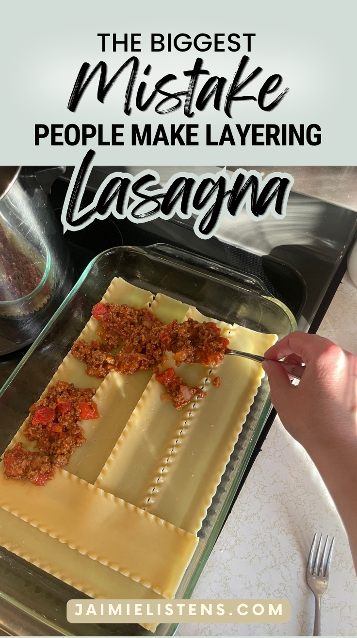 Lasagna noodles layered in a glass baking dish with slight overlap and trimmed with mix being added on top.